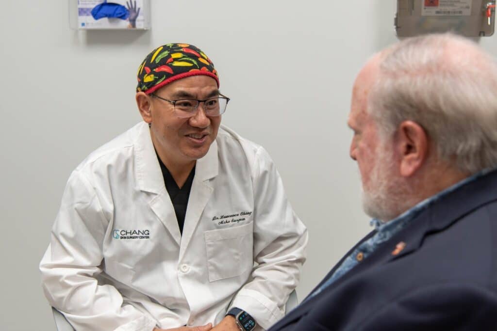 chang-derm-cta-photo Dr. Chang smiling talking to an older male patient