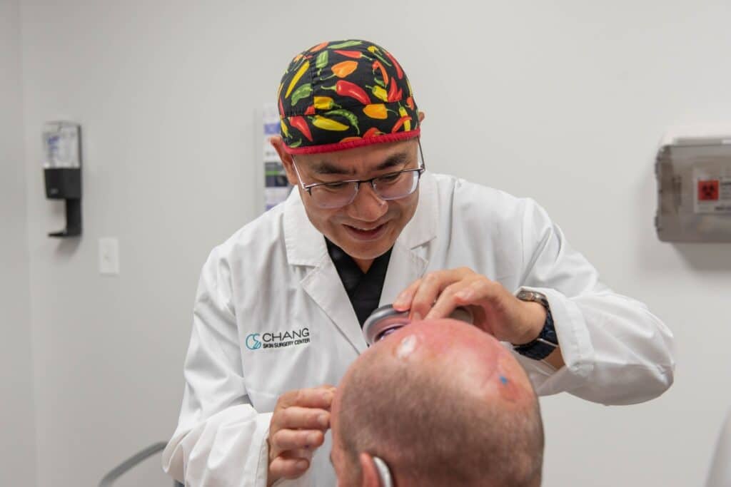 Dr. Lawrence inspecting a patient's skin on his head.
