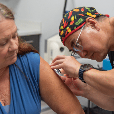 Dr. Chang inspecting a patient's arm with a magnifying glass, representing what to expect during a skin biopsy