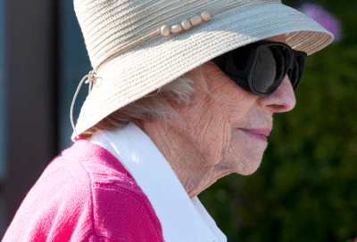 Elderly woman in hat and sunglasses. representing sun protection after skin surgery
