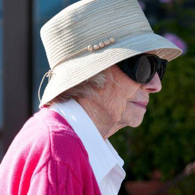 Elderly woman in hat and sunglasses. representing sun protection after skin surgery